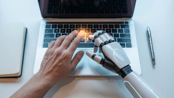 Mano umana e mano robotica digitano insieme sulla tastiera di un laptop, simbolo della collaborazione tra uomo e intelligenza artificiale